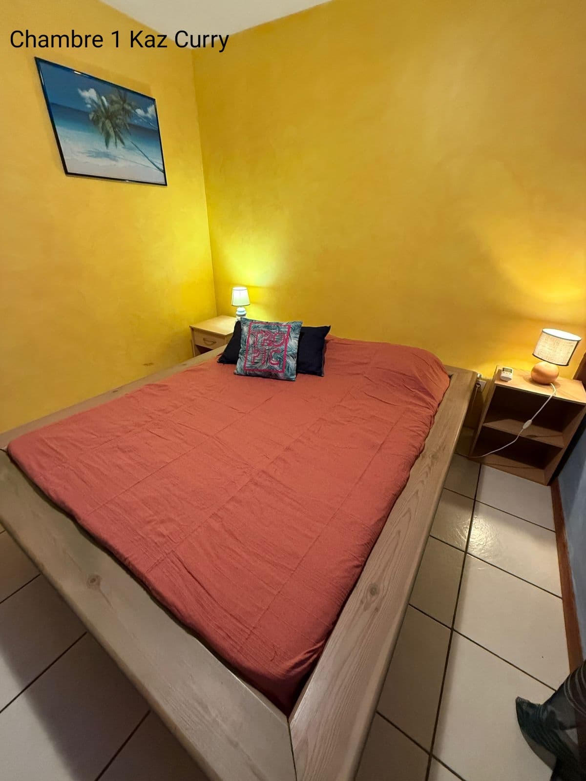 Chambre 1 de Kaz Curry, murs jaunes et lit rouge