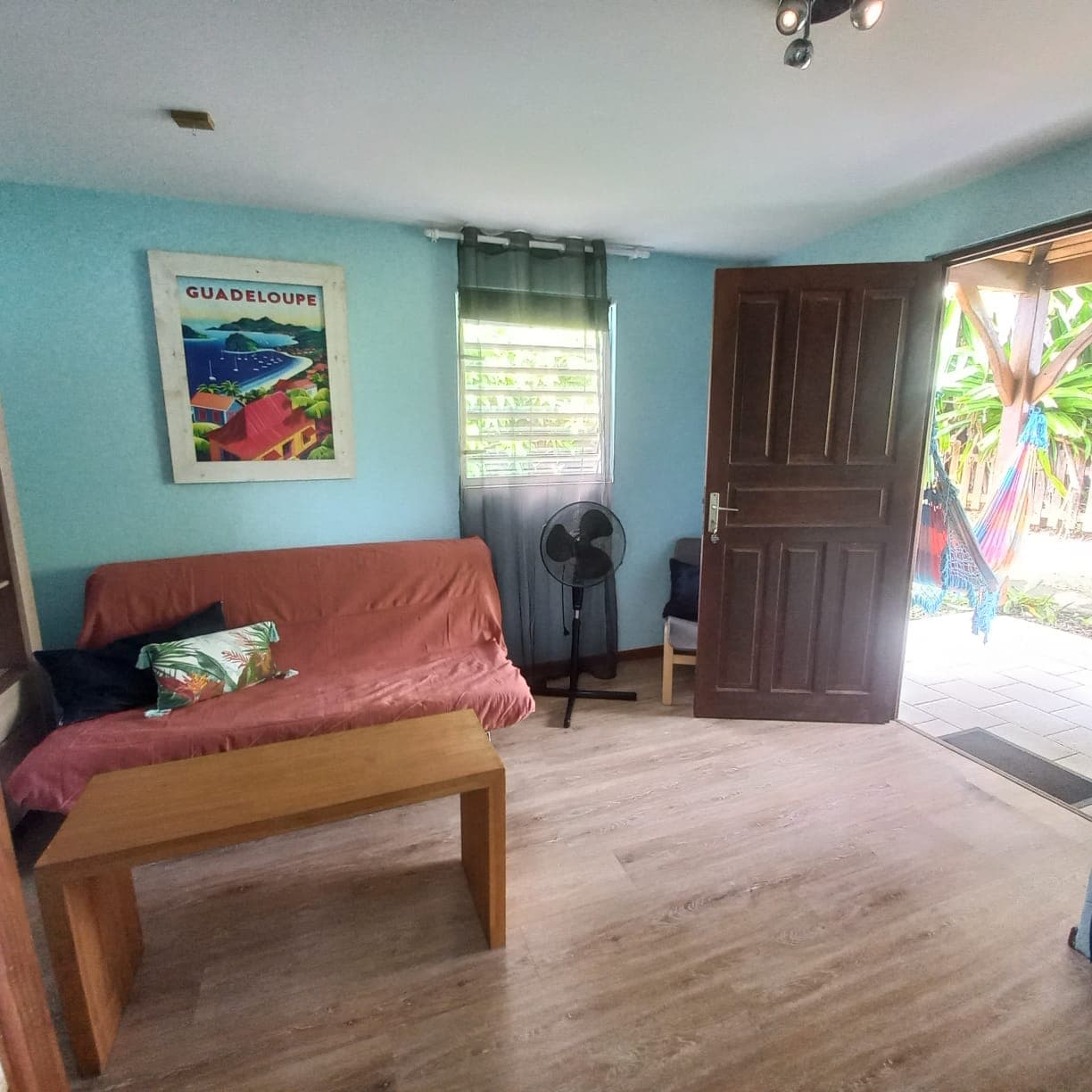 Séjour aux murs turquoise avec son futon rouge