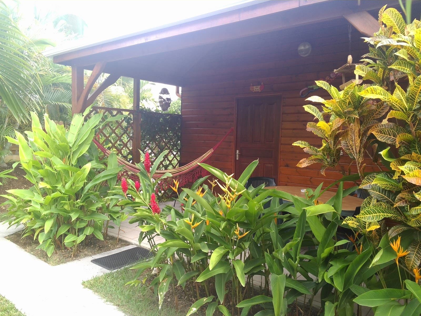 Façade d'un bungalow en bois bordée de fleurs tropicales
